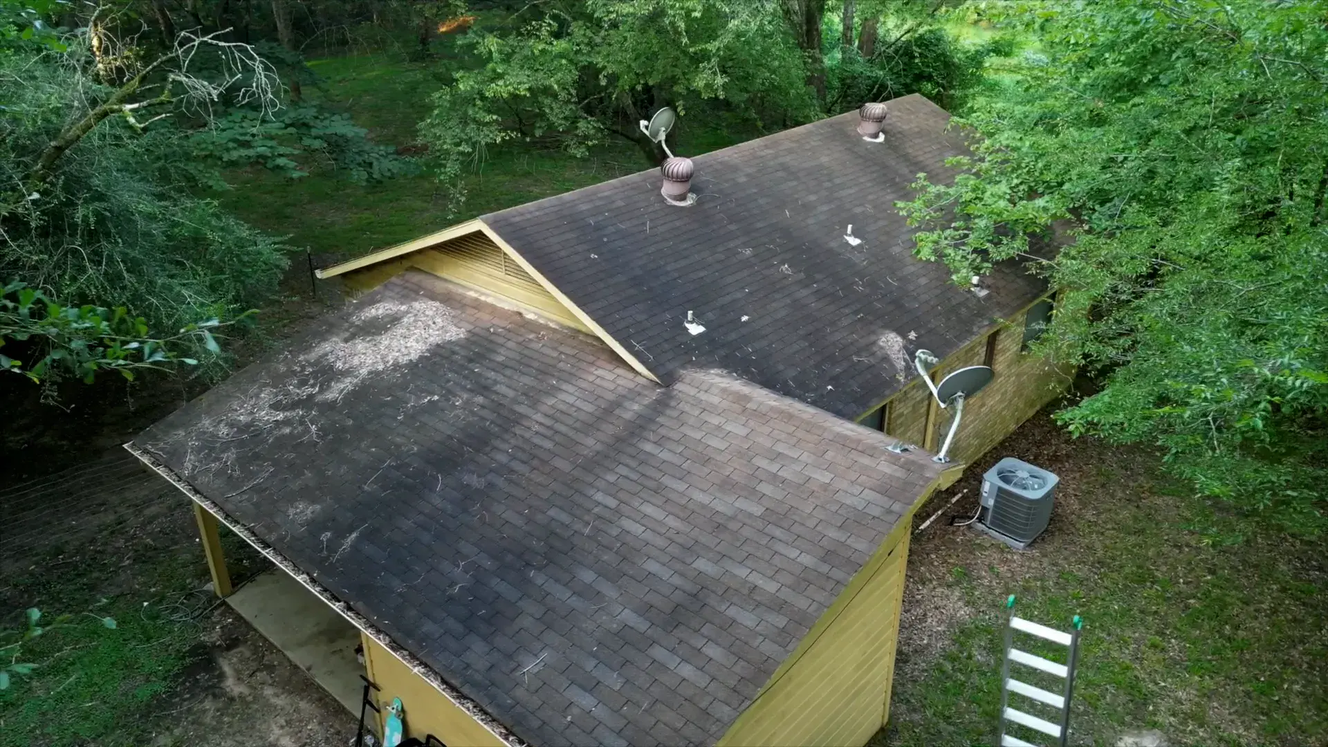 Weathered yellow wood siding and worn eaves on an older Arkansas home before repairs